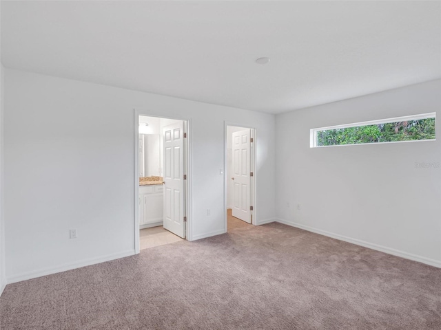 unfurnished bedroom featuring light colored carpet and connected bathroom