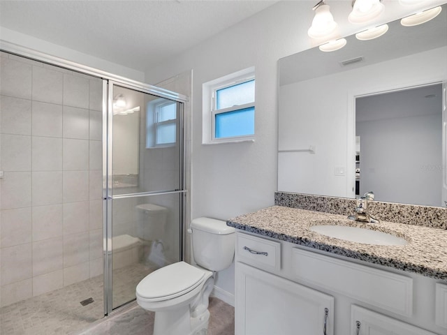 bathroom with a shower with shower door, toilet, and vanity