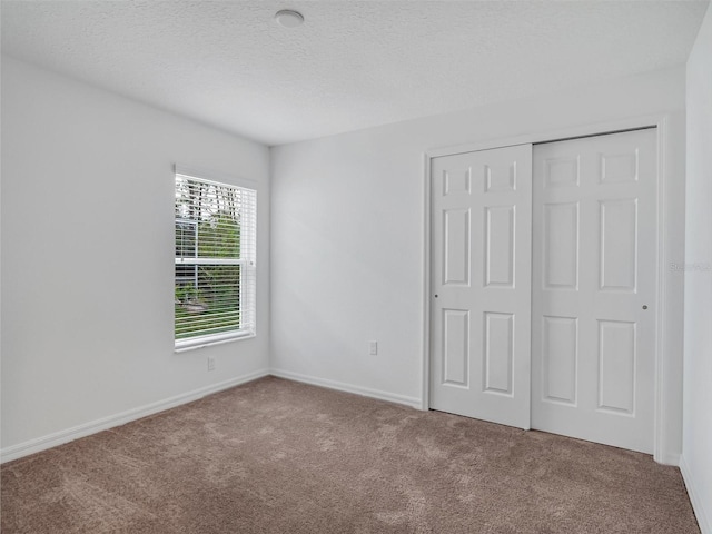 unfurnished bedroom with carpet floors, a textured ceiling, and a closet