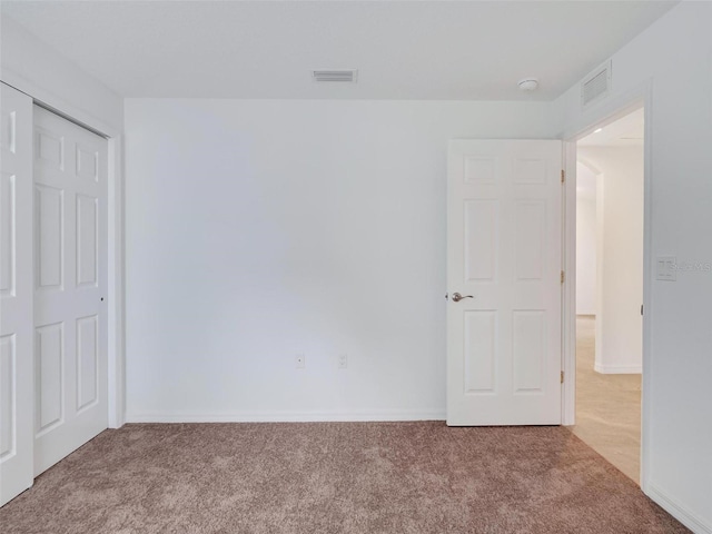 unfurnished bedroom with light colored carpet and a closet