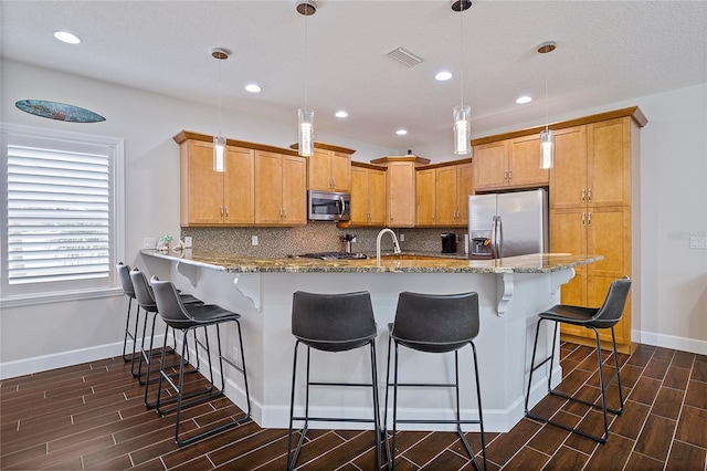 kitchen featuring light stone countertops, decorative light fixtures, stainless steel appliances, tasteful backsplash, and kitchen peninsula