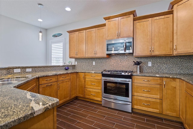 kitchen with sink, hanging light fixtures, stainless steel appliances, and tasteful backsplash