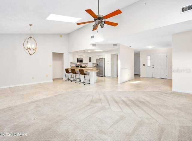 tiled living room with vaulted ceiling and ceiling fan with notable chandelier