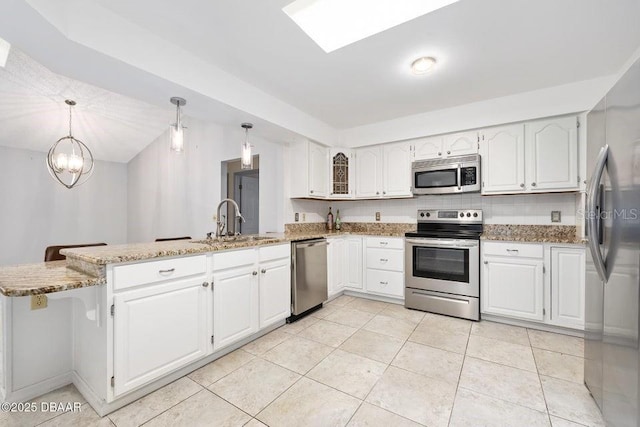 kitchen with white cabinets, pendant lighting, appliances with stainless steel finishes, and kitchen peninsula