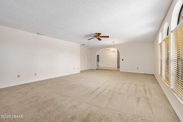 carpeted empty room with ceiling fan and a textured ceiling