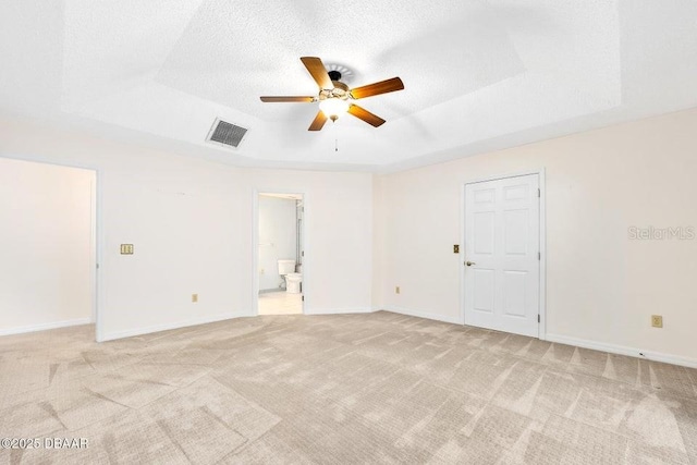 carpeted spare room featuring ceiling fan, a textured ceiling, and a tray ceiling