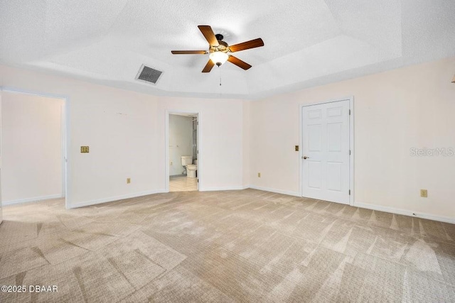 carpeted empty room featuring a raised ceiling, ceiling fan, and a textured ceiling