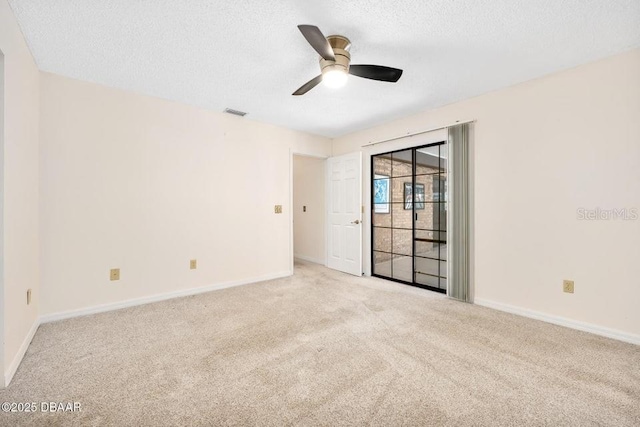 empty room featuring ceiling fan, light colored carpet, and a textured ceiling