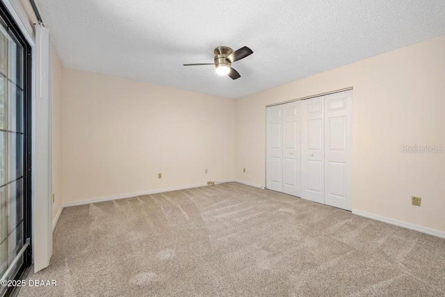 unfurnished bedroom with ceiling fan, a closet, light carpet, and a textured ceiling