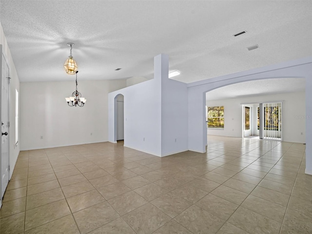 tiled spare room with a notable chandelier