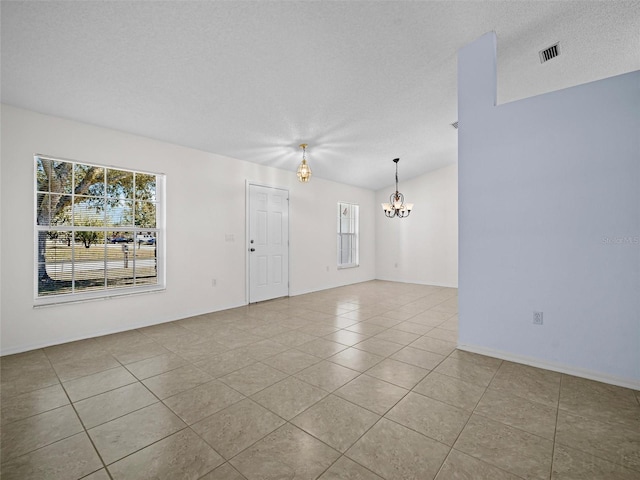 tiled spare room with lofted ceiling, an inviting chandelier, and a textured ceiling