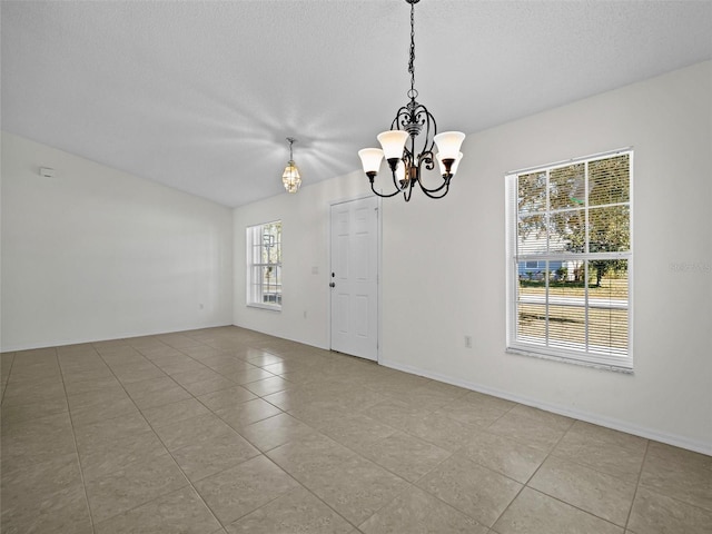 tiled spare room featuring a notable chandelier and a textured ceiling