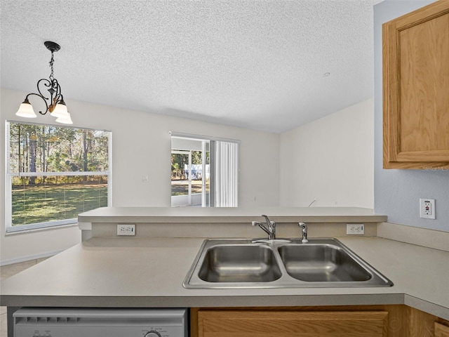 kitchen featuring pendant lighting, sink, a textured ceiling, dishwashing machine, and a chandelier