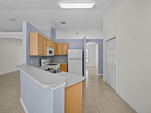 kitchen with a textured ceiling, light tile patterned floors, kitchen peninsula, and white appliances