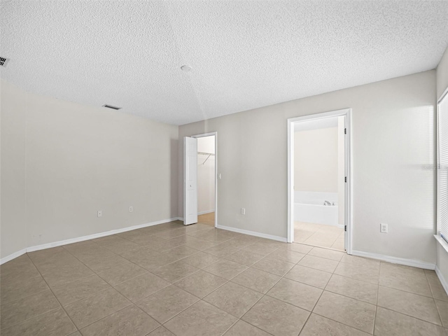 tiled empty room with a textured ceiling