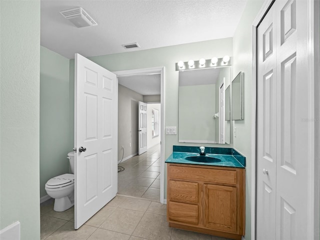 bathroom with a textured ceiling, tile patterned floors, vanity, and toilet