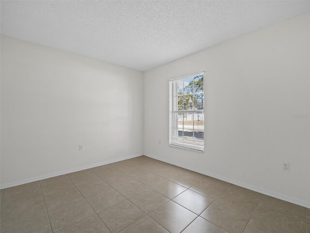 spare room with a textured ceiling and light tile patterned floors