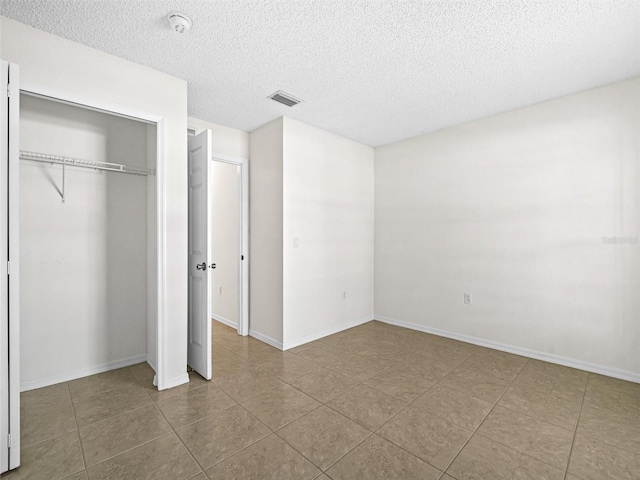 unfurnished bedroom with a closet, tile patterned floors, and a textured ceiling