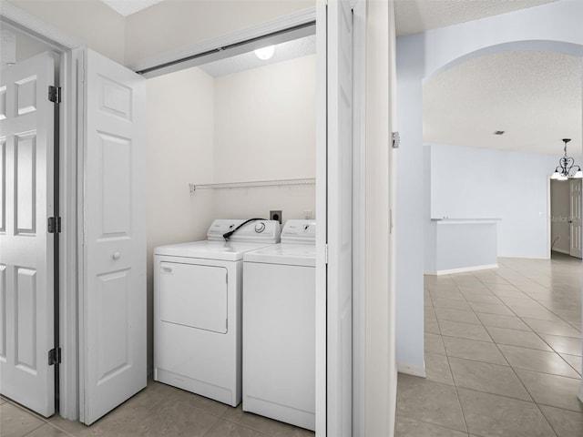 washroom with a notable chandelier, light tile patterned flooring, separate washer and dryer, and a textured ceiling