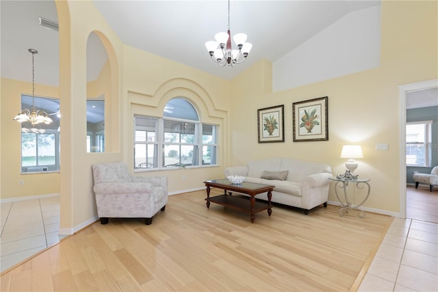 living room featuring high vaulted ceiling, light wood-type flooring, and an inviting chandelier