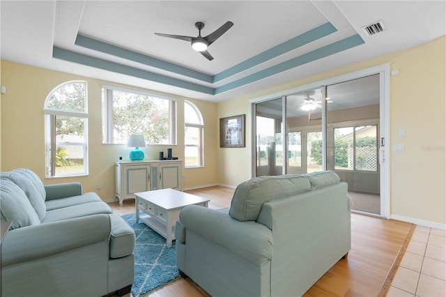 living room featuring ceiling fan, light tile patterned floors, and a tray ceiling