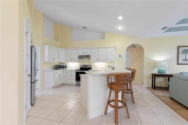 kitchen with appliances with stainless steel finishes, a kitchen bar, white cabinetry, sink, and light tile patterned floors