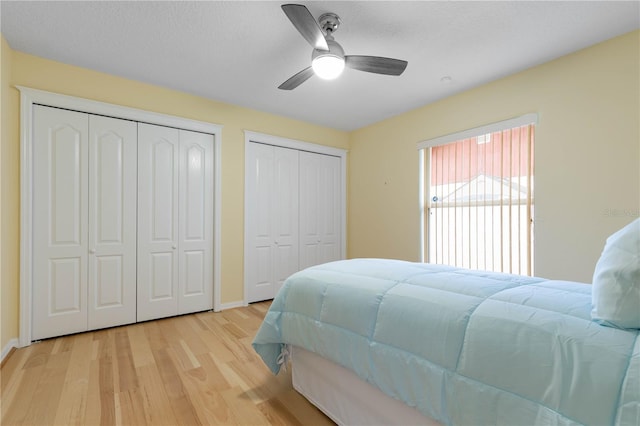 bedroom featuring ceiling fan, light hardwood / wood-style floors, and two closets