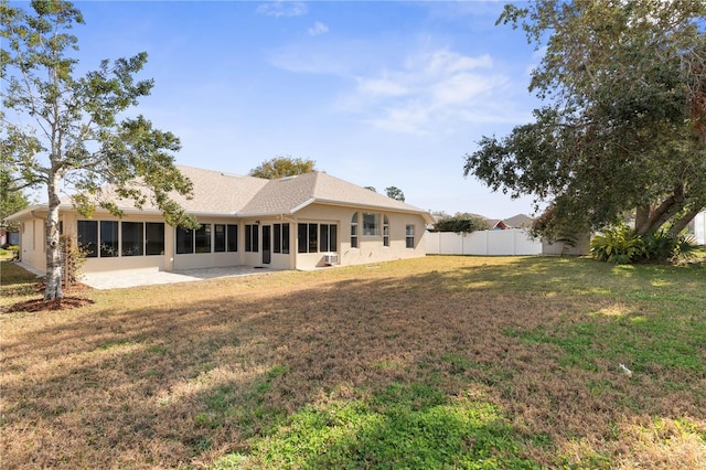 rear view of house with a yard, a sunroom, and a patio