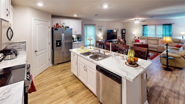 kitchen with sink, white cabinetry, stainless steel appliances, an island with sink, and light wood-type flooring