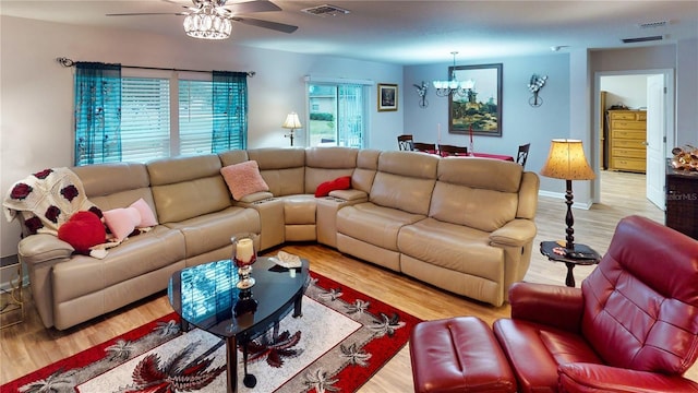 living room featuring ceiling fan with notable chandelier and light wood-type flooring