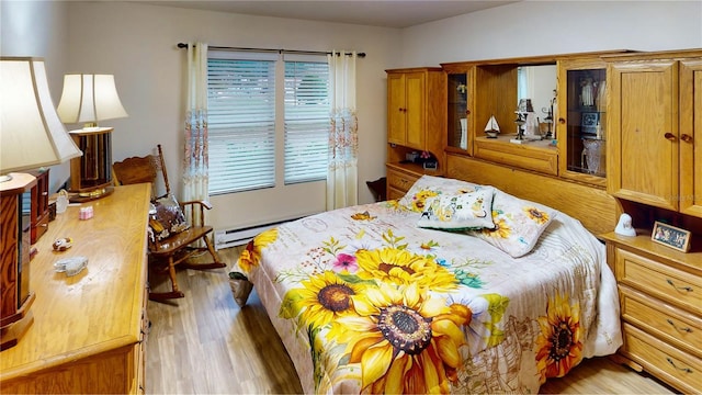 bedroom featuring a baseboard heating unit and light wood-type flooring