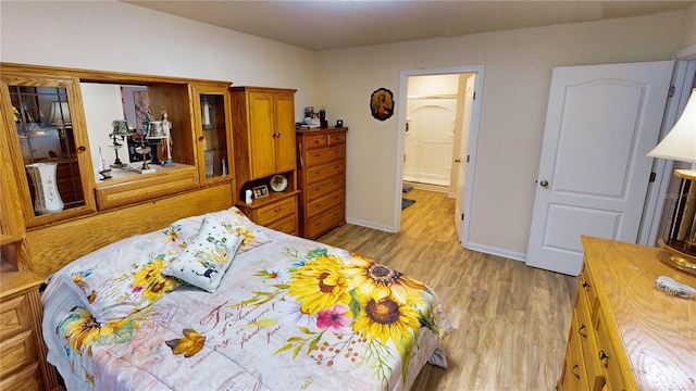 bedroom with ensuite bathroom and light wood-type flooring