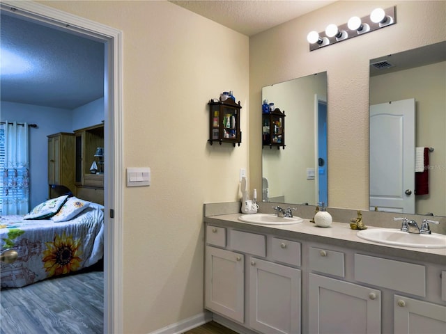 bathroom with hardwood / wood-style flooring, vanity, and a textured ceiling