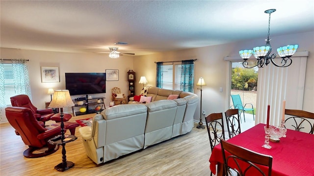 living room with ceiling fan with notable chandelier, light hardwood / wood-style flooring, and plenty of natural light