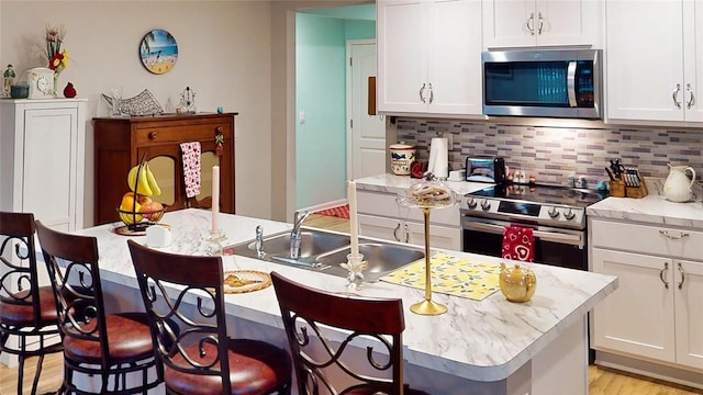 kitchen with white cabinetry, appliances with stainless steel finishes, a kitchen island with sink, and sink