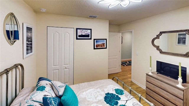 bedroom with hardwood / wood-style floors, a textured ceiling, and a closet