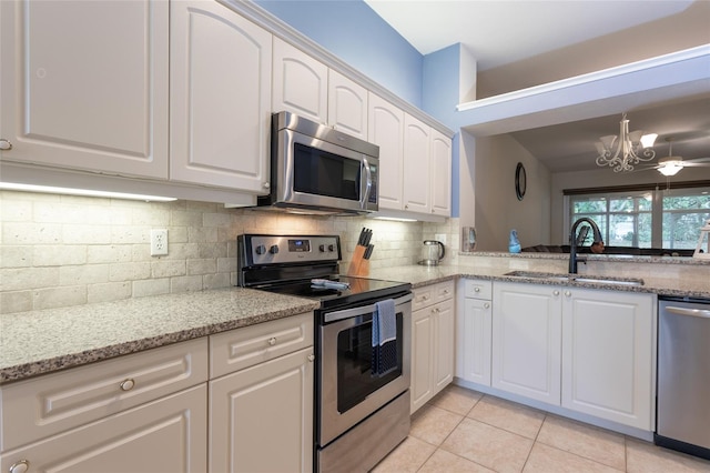 kitchen featuring light stone countertops, white cabinetry, stainless steel appliances, tasteful backsplash, and sink