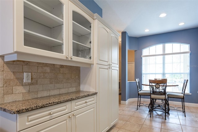 kitchen with a wealth of natural light, white cabinetry, decorative backsplash, and dark stone counters