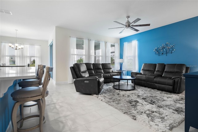 living room with ceiling fan with notable chandelier and plenty of natural light