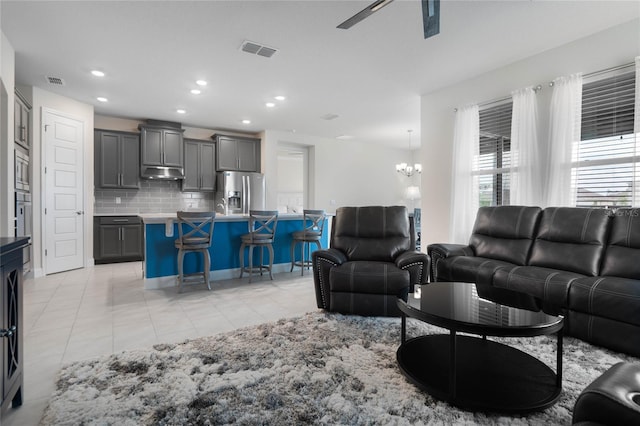 living room with light tile patterned floors and ceiling fan with notable chandelier