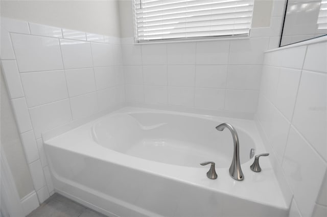 bathroom with a healthy amount of sunlight, tile patterned floors, and a washtub