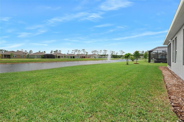 view of yard with glass enclosure and a water view