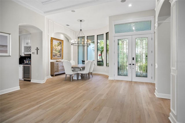 unfurnished dining area with french doors, an inviting chandelier, light hardwood / wood-style floors, wine cooler, and ornamental molding