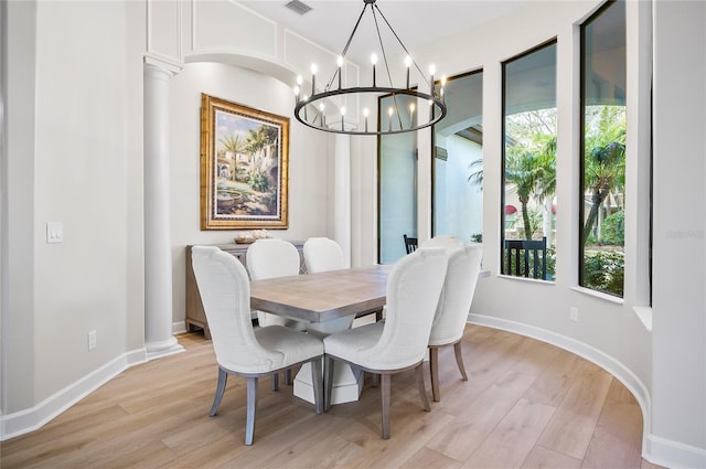 dining space featuring a notable chandelier, decorative columns, and light hardwood / wood-style flooring