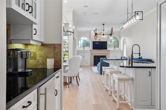 kitchen with a breakfast bar area, crown molding, white cabinets, and decorative light fixtures