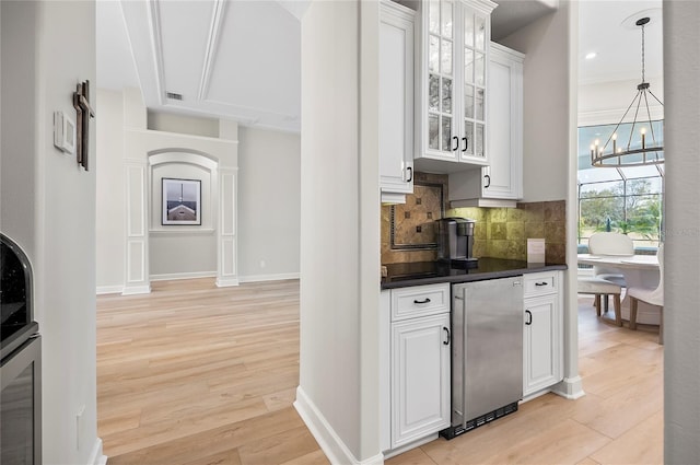 bar featuring backsplash, light hardwood / wood-style flooring, white cabinets, stainless steel fridge, and a chandelier