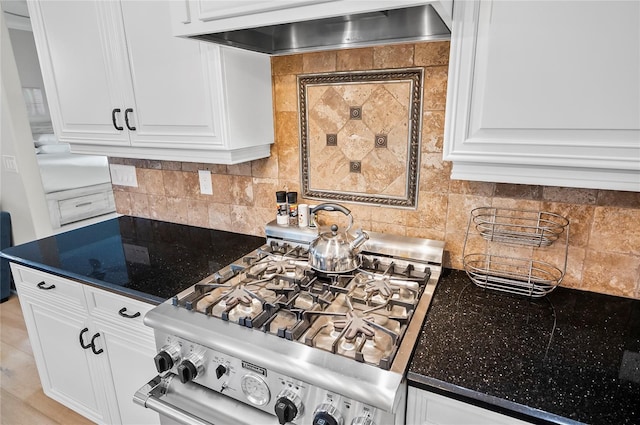 kitchen featuring tasteful backsplash, white cabinets, stainless steel gas range oven, and wall chimney range hood