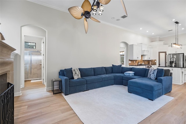 living room with ceiling fan, crown molding, and light hardwood / wood-style floors