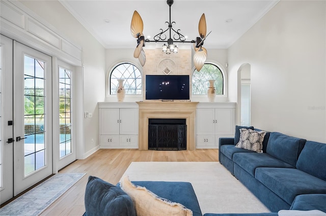 living room with light wood-type flooring, a notable chandelier, and ornamental molding