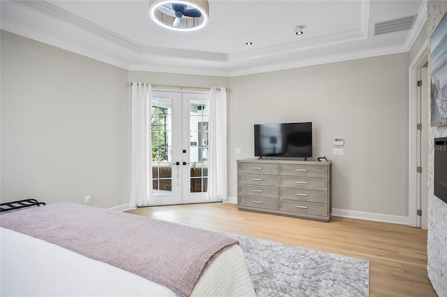 bedroom featuring light hardwood / wood-style floors, access to exterior, a raised ceiling, and french doors